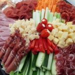 A colourful platter of vegetable sticks, rolled ham, salami and cubes of cheese.