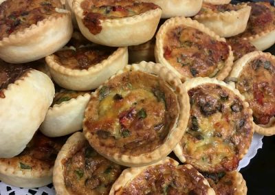 A plate piled high with mixed mini-quiches.